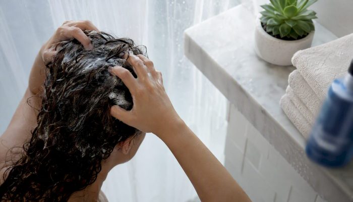 Hands massaging shampoo into hair under natural light