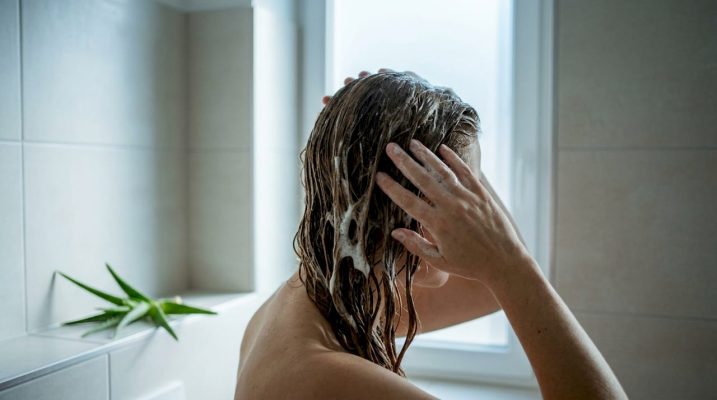 Hands soaking hair strand in aloe water solution