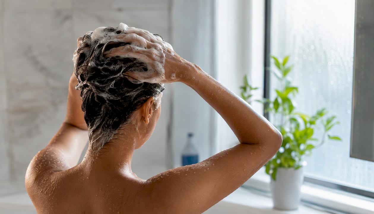 Hands applying shampoo to wet hair strand
