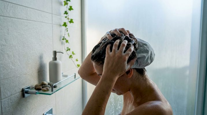 Hands applying shampoo to hair at bathroom sink