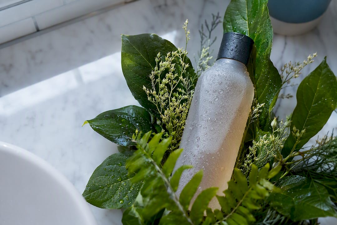 Shampoo bottle with leaves on bathroom shelf
