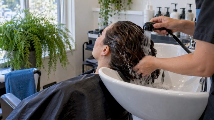 Client rinsing hair at a salon basin