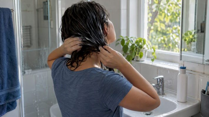 Woman conditioning damp hair after washing